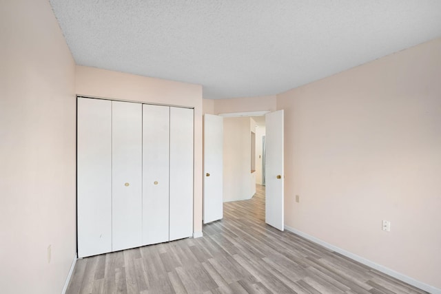 unfurnished bedroom featuring a textured ceiling, light wood-type flooring, and a closet