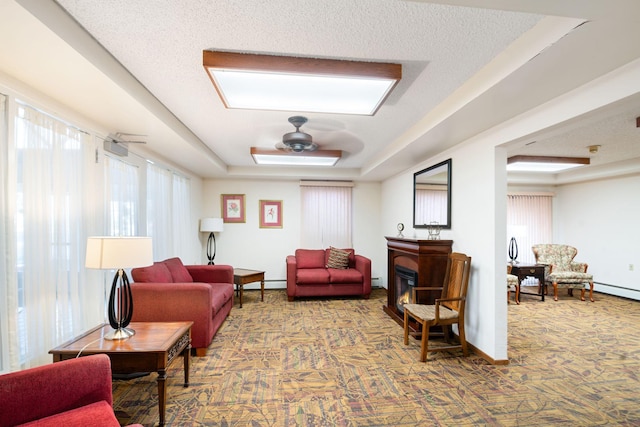 living room with a textured ceiling, a baseboard radiator, a raised ceiling, and ceiling fan