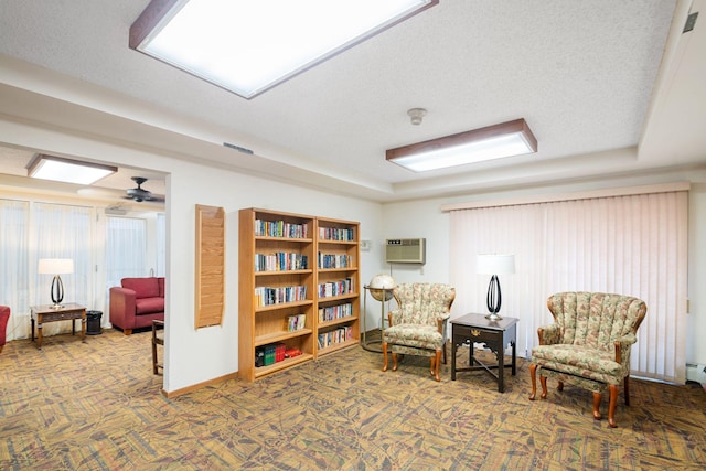 living area featuring ceiling fan, a wall mounted air conditioner, carpet, and a textured ceiling