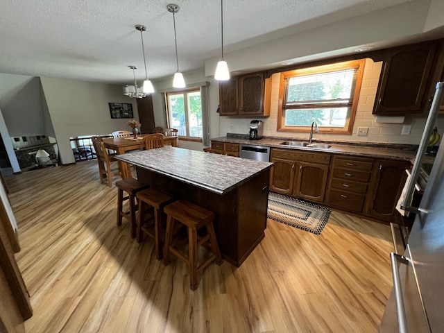 kitchen with tasteful backsplash, a center island, light wood-type flooring, and sink