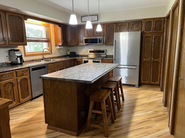 kitchen with a kitchen island, sink, stainless steel appliances, and light hardwood / wood-style flooring