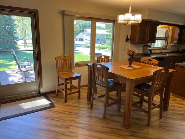 dining area featuring a notable chandelier, sink, a wealth of natural light, and light hardwood / wood-style flooring