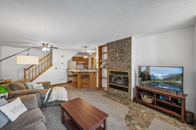 living room with ceiling fan, a textured ceiling, and a fireplace