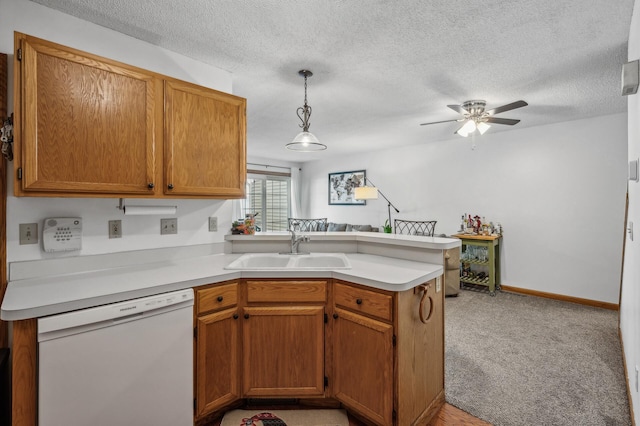 kitchen with sink, dishwasher, kitchen peninsula, pendant lighting, and light colored carpet