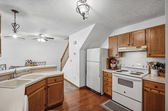 kitchen featuring dark hardwood / wood-style floors, sink, hanging light fixtures, white appliances, and a textured ceiling