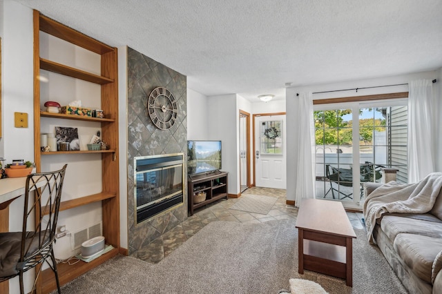 carpeted living room featuring built in shelves, visible vents, a tiled fireplace, a textured ceiling, and baseboards