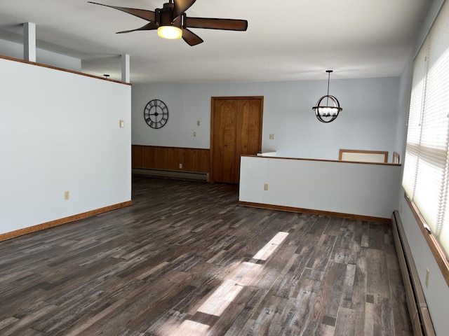 empty room featuring dark hardwood / wood-style floors, a wealth of natural light, and a baseboard heating unit