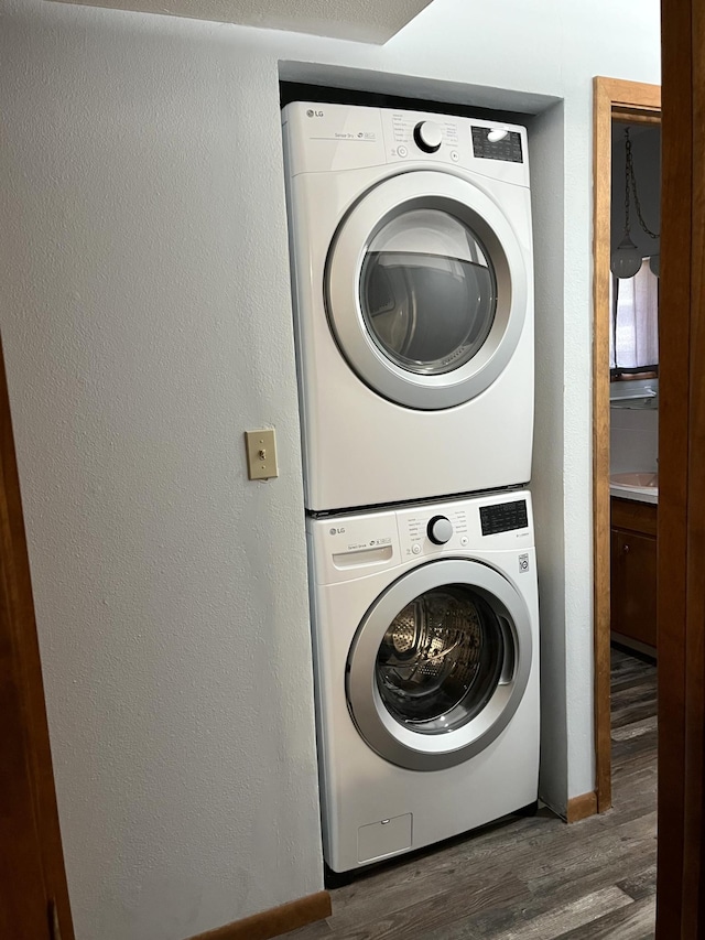 washroom featuring dark hardwood / wood-style flooring and stacked washer / drying machine