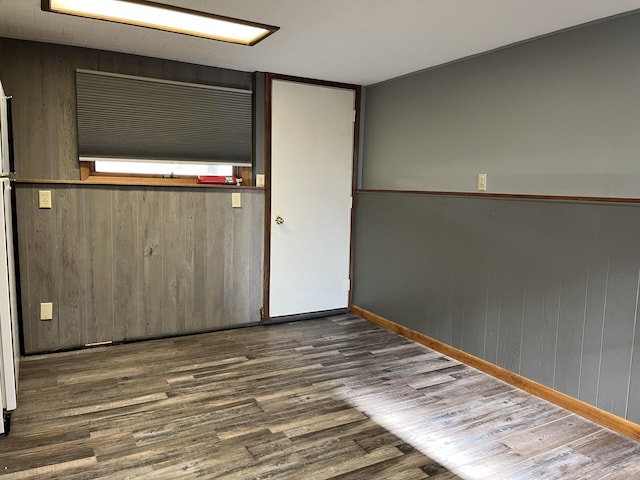 spare room with dark wood-type flooring and wood walls