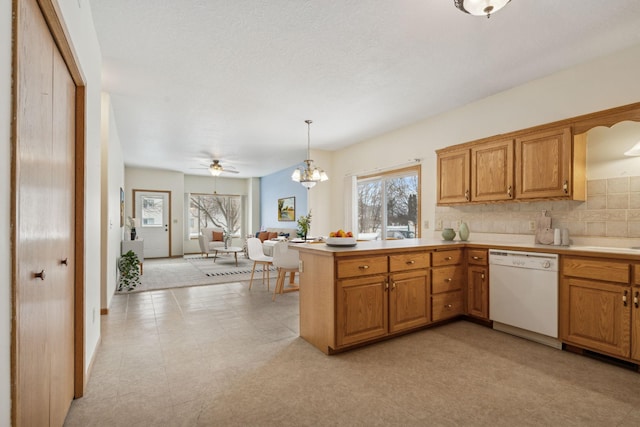 kitchen featuring white dishwasher, decorative backsplash, hanging light fixtures, and a wealth of natural light