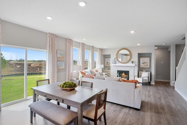 dining area with a stone fireplace, a healthy amount of sunlight, and wood-type flooring