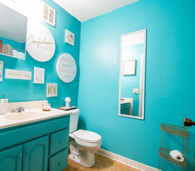 bathroom with tile patterned floors, vanity, toilet, and a textured ceiling