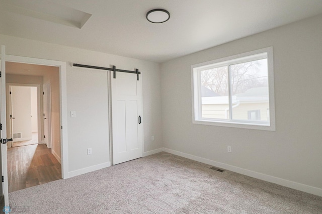 unfurnished bedroom featuring a barn door and carpet