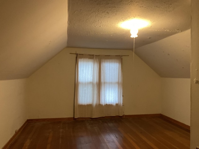 bonus room featuring a textured ceiling, vaulted ceiling, and dark wood-type flooring