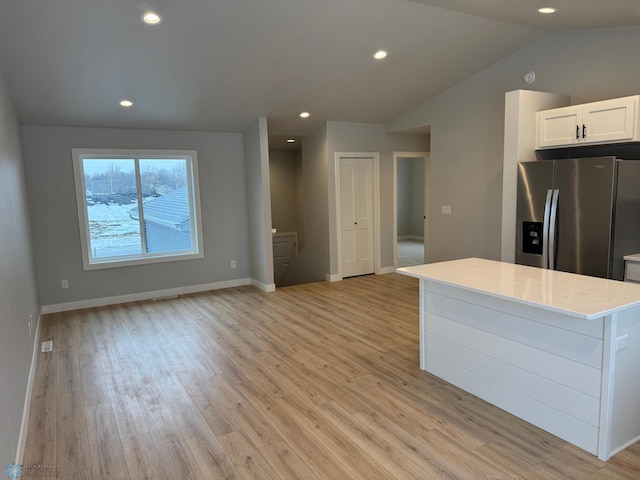 kitchen featuring light stone counters, vaulted ceiling, stainless steel fridge with ice dispenser, light hardwood / wood-style floors, and white cabinetry