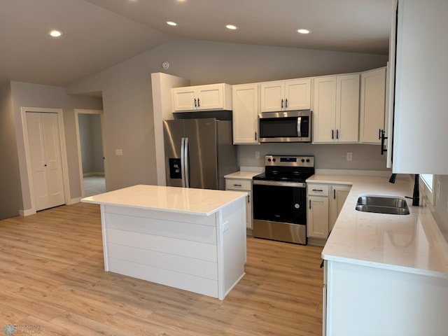 kitchen with light wood-type flooring, stainless steel appliances, a center island, white cabinetry, and lofted ceiling