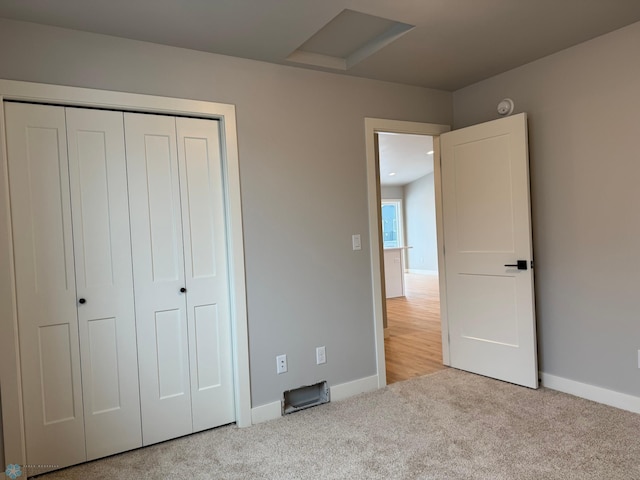 unfurnished bedroom with light carpet and a closet