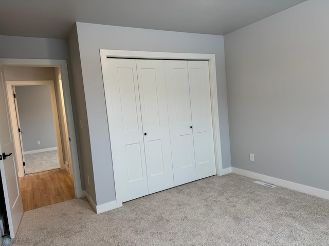 unfurnished bedroom with light carpet and a closet