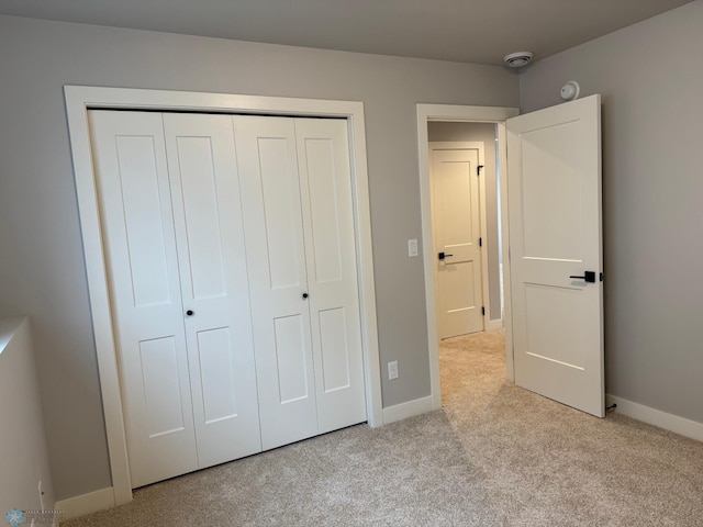 unfurnished bedroom featuring light carpet and a closet