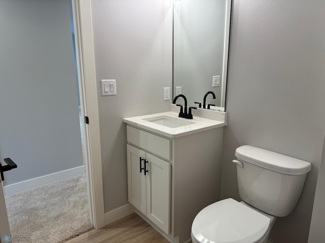 bathroom with hardwood / wood-style floors, vanity, and toilet