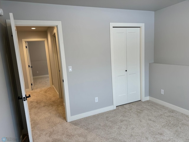 unfurnished bedroom featuring light colored carpet and a closet