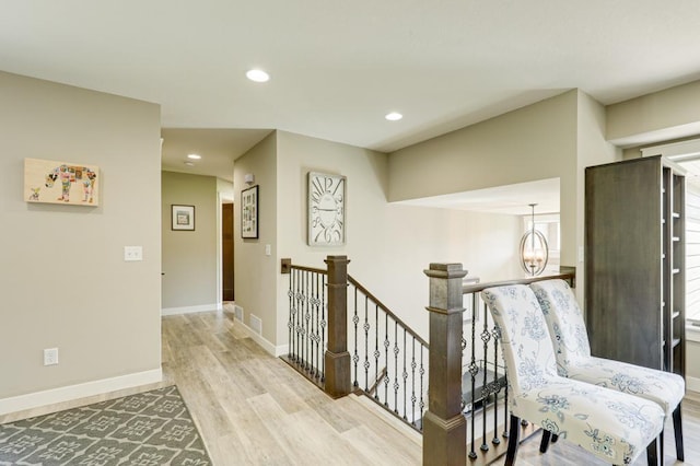 hallway with light hardwood / wood-style flooring and an inviting chandelier