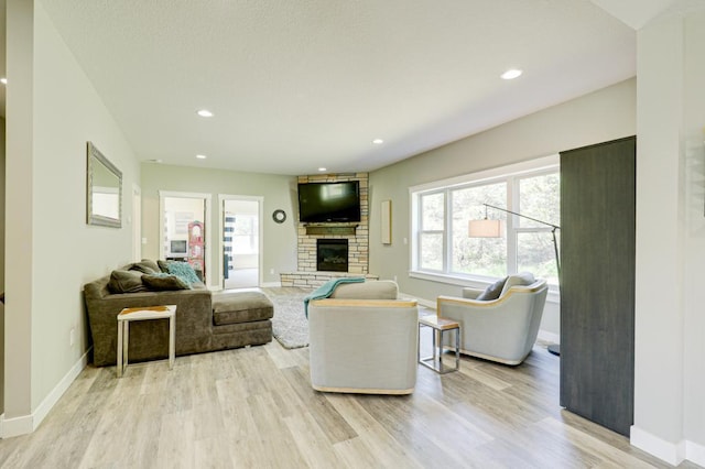 living room with a fireplace, light hardwood / wood-style flooring, and a wealth of natural light