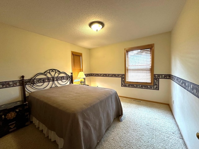 bedroom with visible vents, a textured ceiling, baseboards, and carpet floors