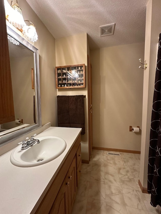 full bathroom featuring visible vents, baseboards, a textured ceiling, and vanity