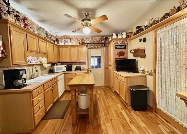 kitchen with a sink, wood counters, a textured ceiling, white appliances, and light wood finished floors