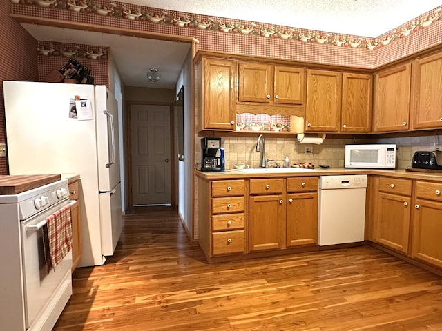 406 Rum River Dr, Princeton, MN 55371 - kitchen featuring white appliances, a sink, light wood-style flooring, and decorative backsplash