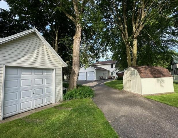 406 Rum River Dr, Princeton, MN 55371 - view of side of property featuring an outbuilding, a detached garage, a lawn, and a storage unit