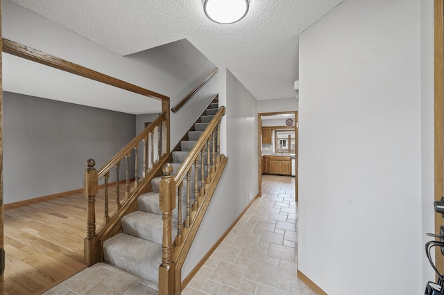 stairs with wood-type flooring and a textured ceiling