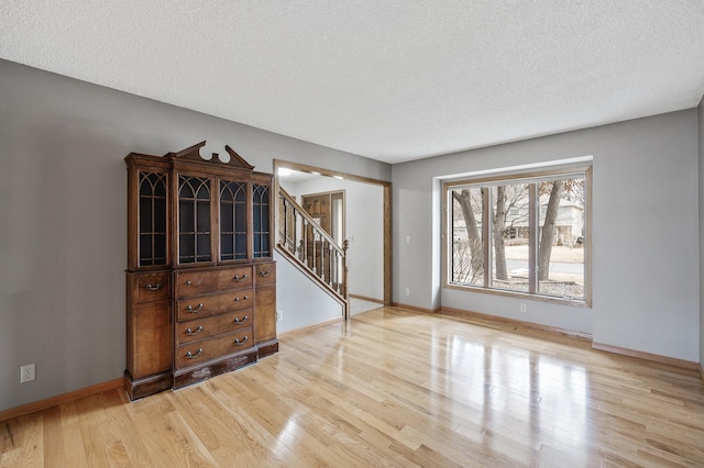 empty room with light hardwood / wood-style flooring and a textured ceiling