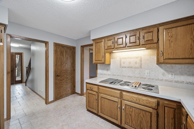 kitchen with backsplash, stovetop, and a textured ceiling