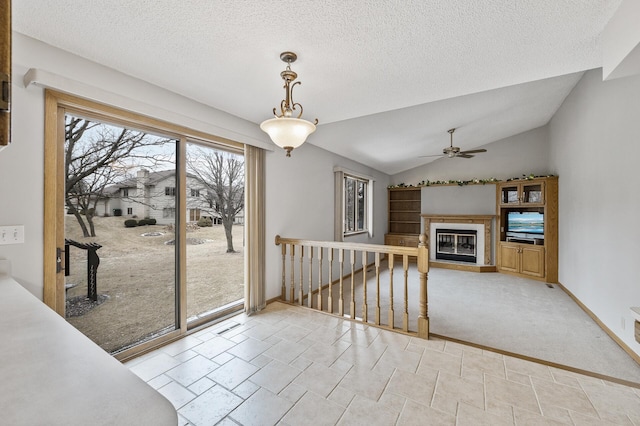 unfurnished living room featuring light colored carpet, ceiling fan, vaulted ceiling, and a textured ceiling