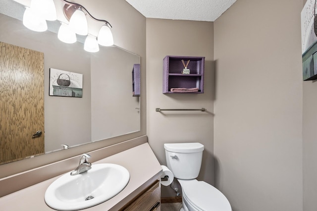 bathroom with vanity, toilet, and a textured ceiling