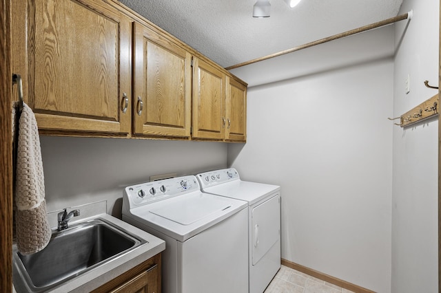 clothes washing area with sink, a textured ceiling, cabinets, and independent washer and dryer