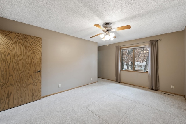 carpeted spare room with a textured ceiling and ceiling fan