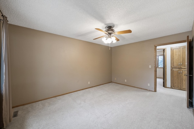 carpeted spare room featuring ceiling fan and a textured ceiling