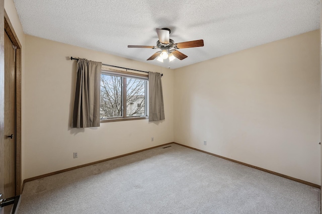 carpeted spare room featuring ceiling fan and a textured ceiling