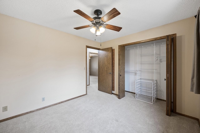 unfurnished bedroom with ceiling fan, light colored carpet, a closet, and a textured ceiling