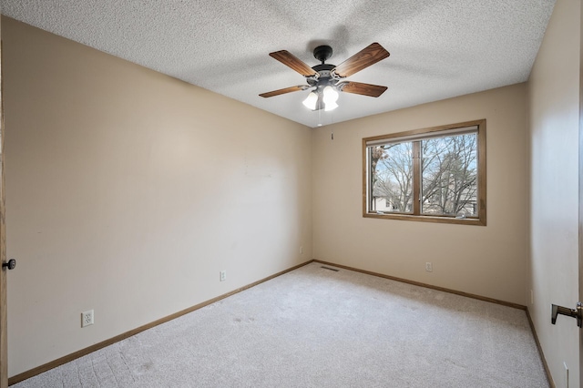 unfurnished room featuring ceiling fan, light colored carpet, and a textured ceiling