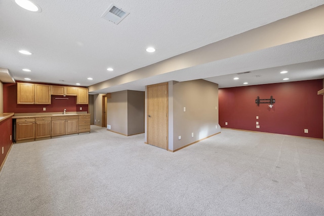 unfurnished living room with sink, light carpet, and a textured ceiling