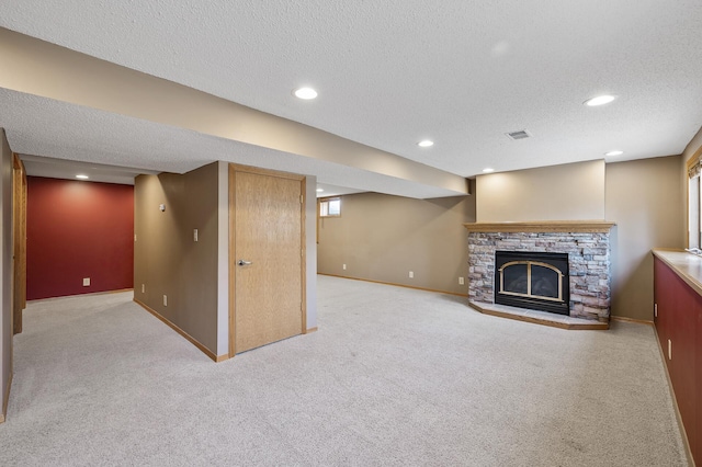 basement featuring a fireplace, light colored carpet, and a textured ceiling