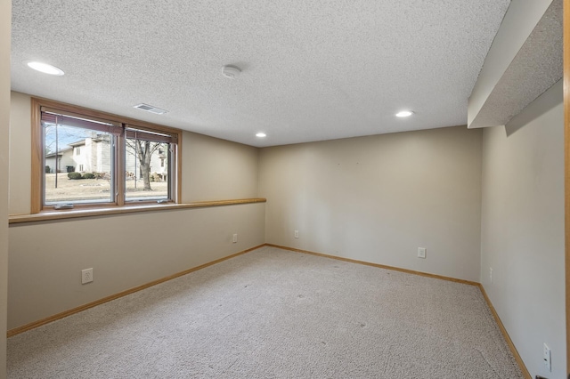 empty room with light colored carpet and a textured ceiling