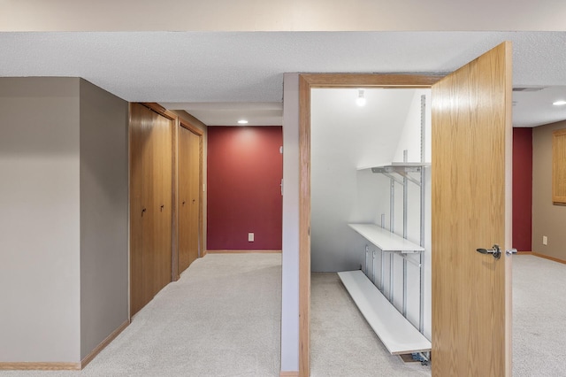 hallway with light colored carpet and a textured ceiling