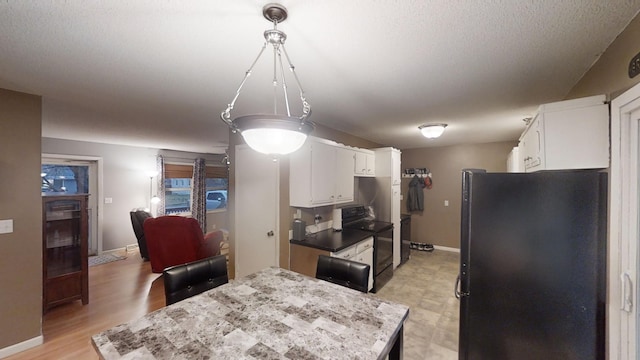 kitchen with a textured ceiling, light hardwood / wood-style floors, white cabinetry, and black appliances