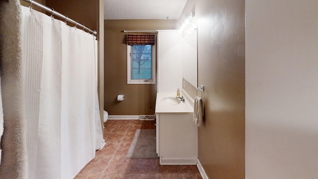 bathroom featuring tile patterned floors, vanity, a textured ceiling, and toilet