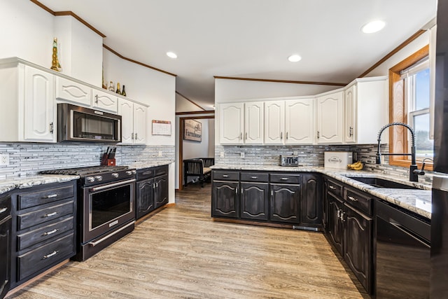 kitchen with light stone counters, sink, light hardwood / wood-style flooring, white cabinets, and stainless steel stove